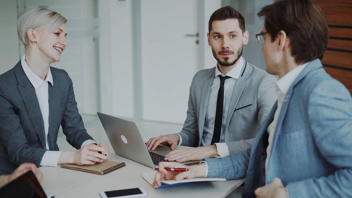 Business professionals in a meeting discussing strategy with laptops and notebooks