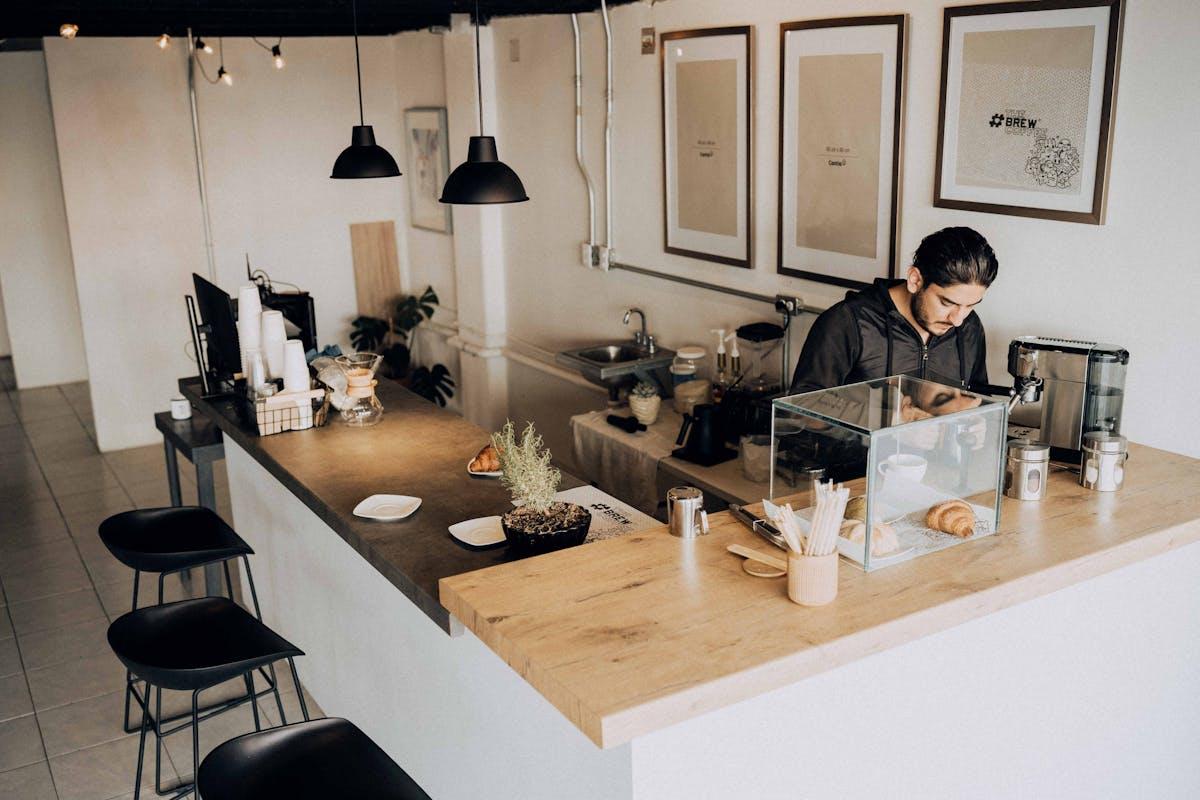 A barista works in a modern cafe with minimalistic decor and warm lighting