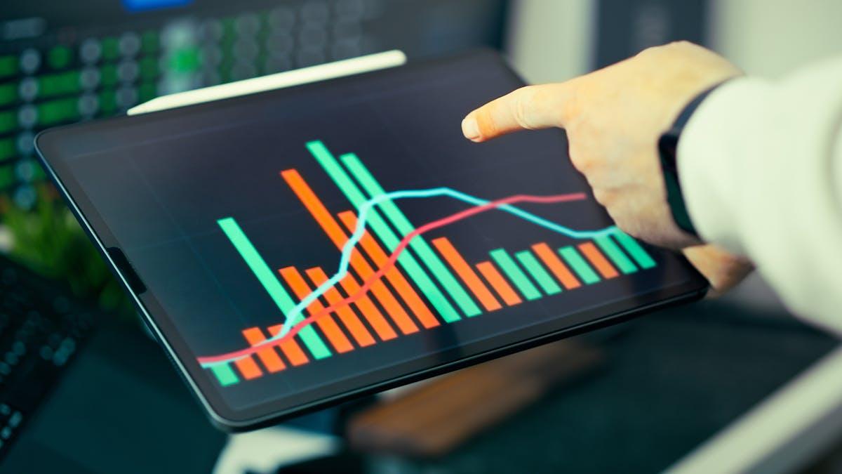 Person analyzing business data with graphs on tablet screen