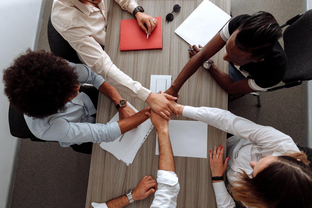Diverse team placing hands together in sign of unity during office meeting