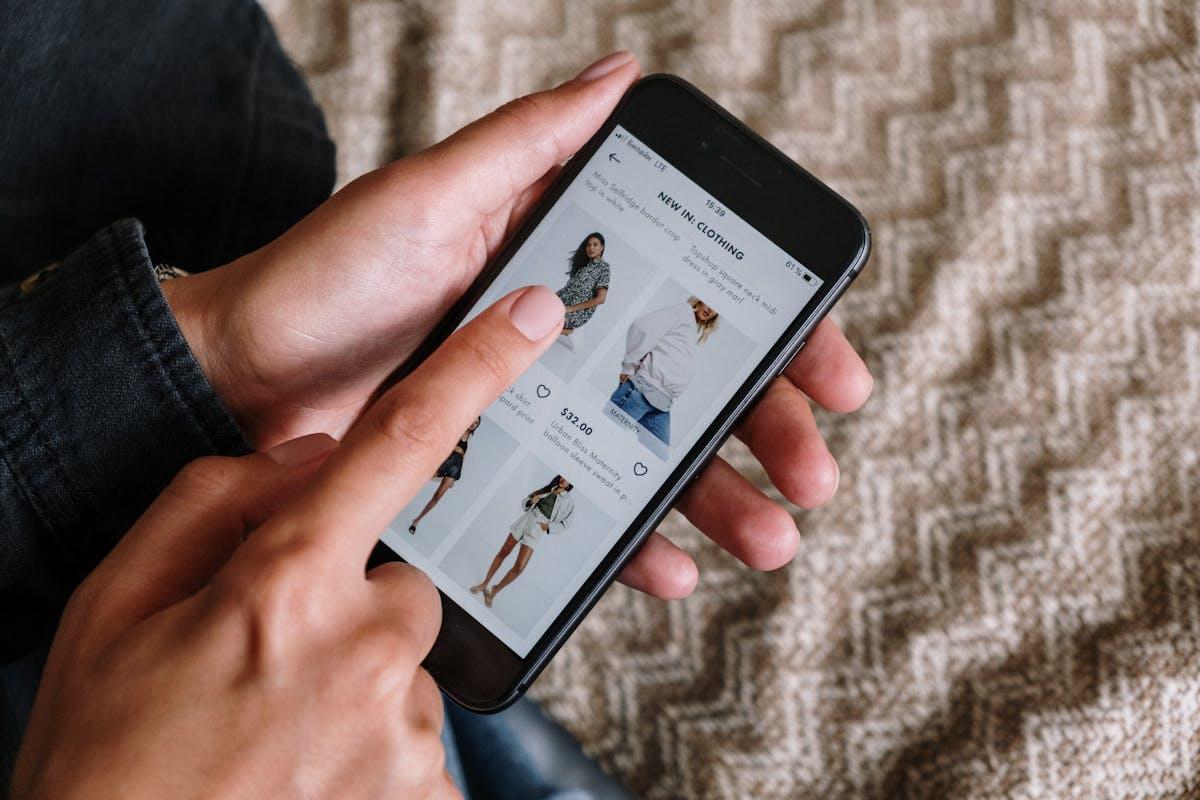 Person browsing clothing items on a smartphone, showcasing modern online shopping experience