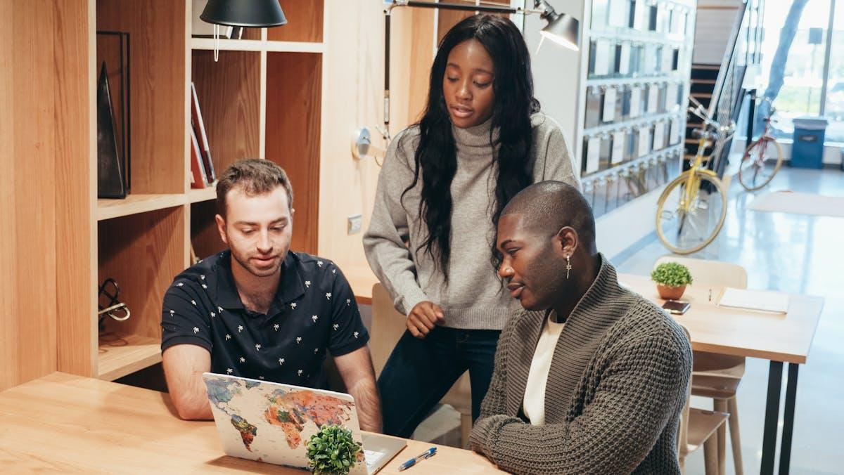 Small team collaborating around laptop in modern office