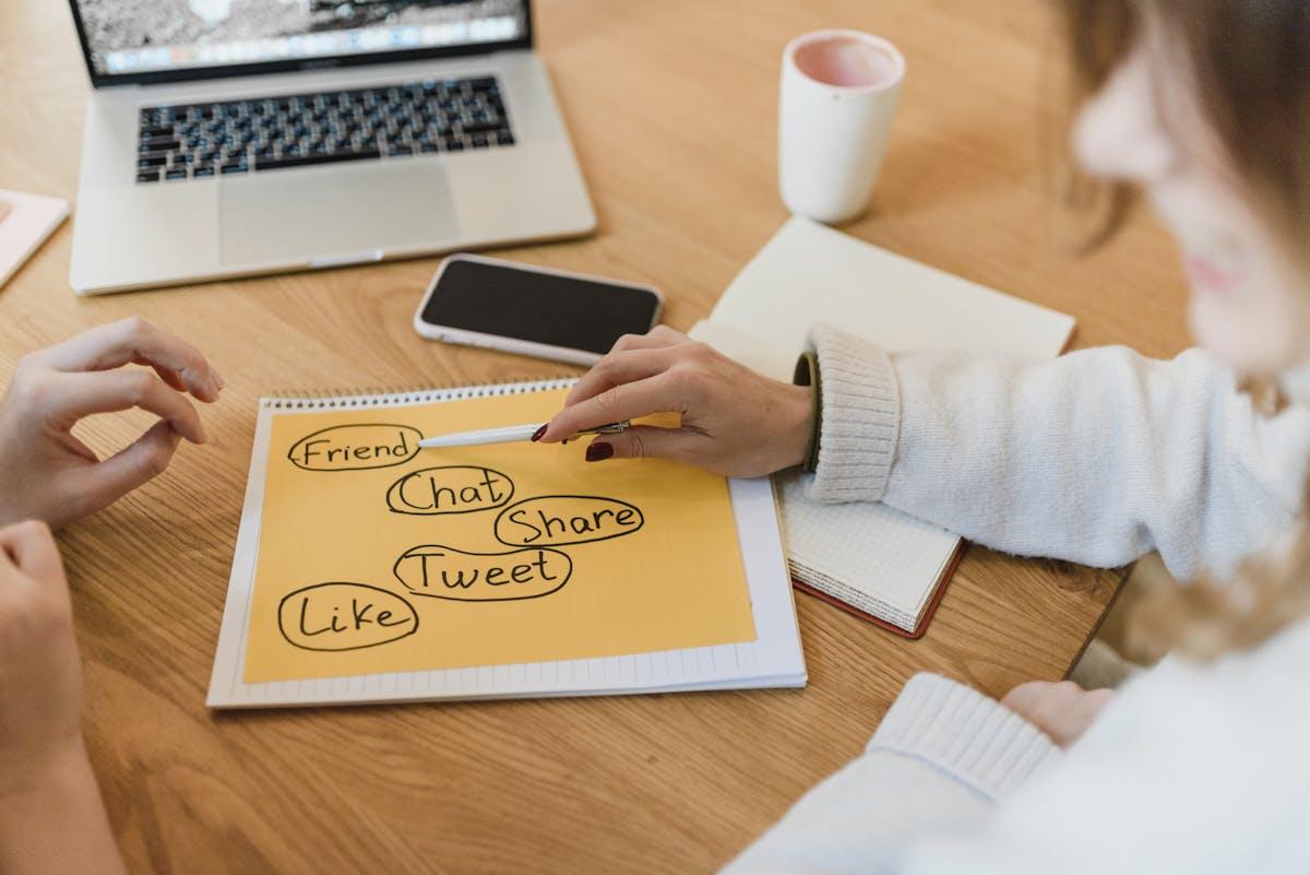 Dve ženski načrtujeta strategijo za družbena omrežja s prenosnikom in pametnim telefonom