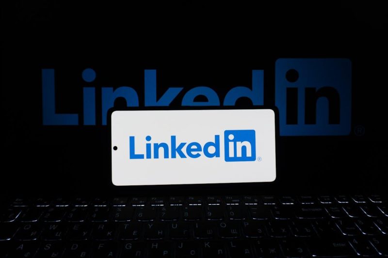 Smartphone showing LinkedIn logo with keyboard in business setting