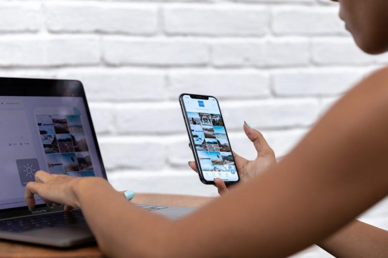 Woman working remotely on social media content using laptop and smartphone