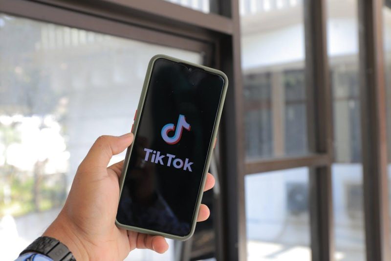 Person holding smartphone displaying TikTok app