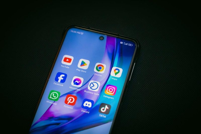 Smartphone displaying TikTok and social media app icons on dark background