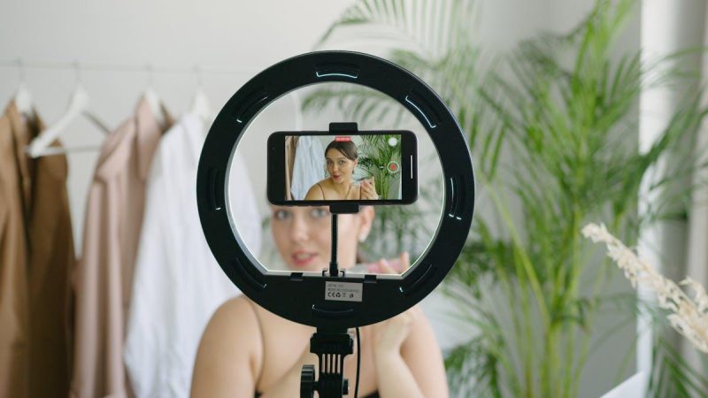 Woman recording video content with smartphone and ring light for social media UGC