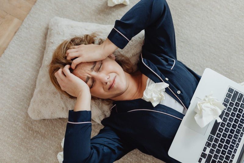 Overhead view of a frustrated woman working remotely with a laptop and crumpled papers
