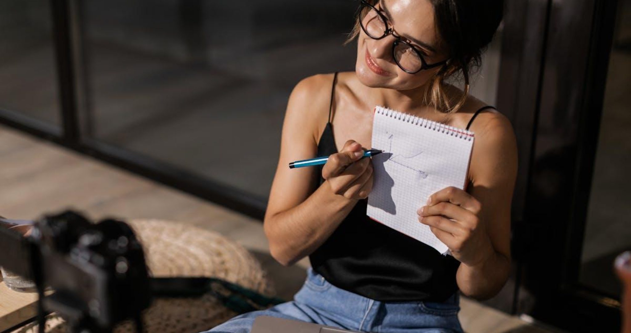 Woman creating content with laptop and camera in home studio, representing social media manager workspace