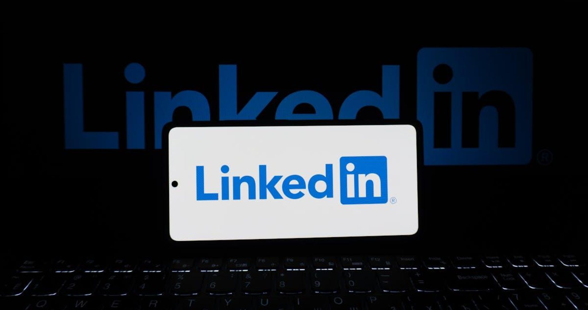 Smartphone showing LinkedIn logo with keyboard in business setting