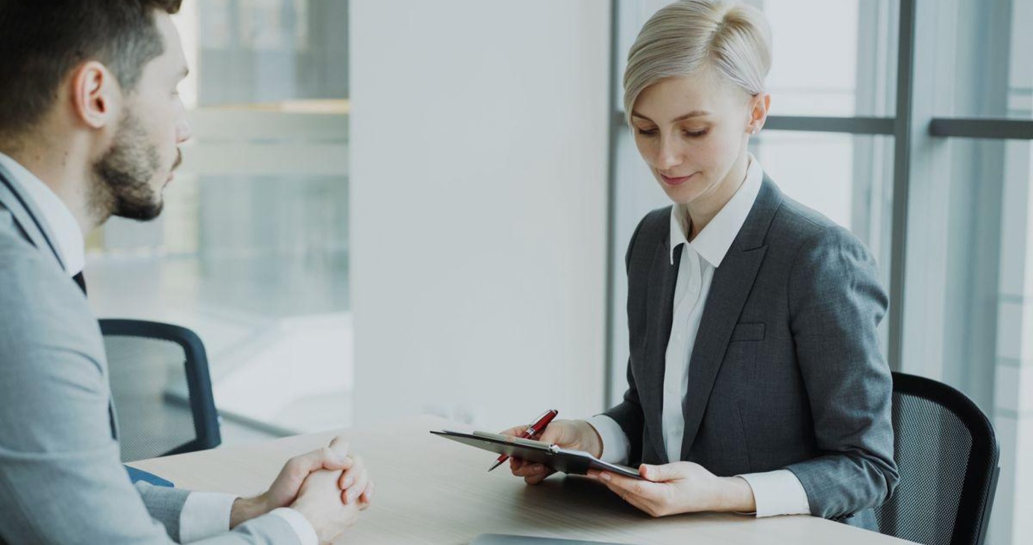 Two professionals in a modern office discussing business for recruiting strategy