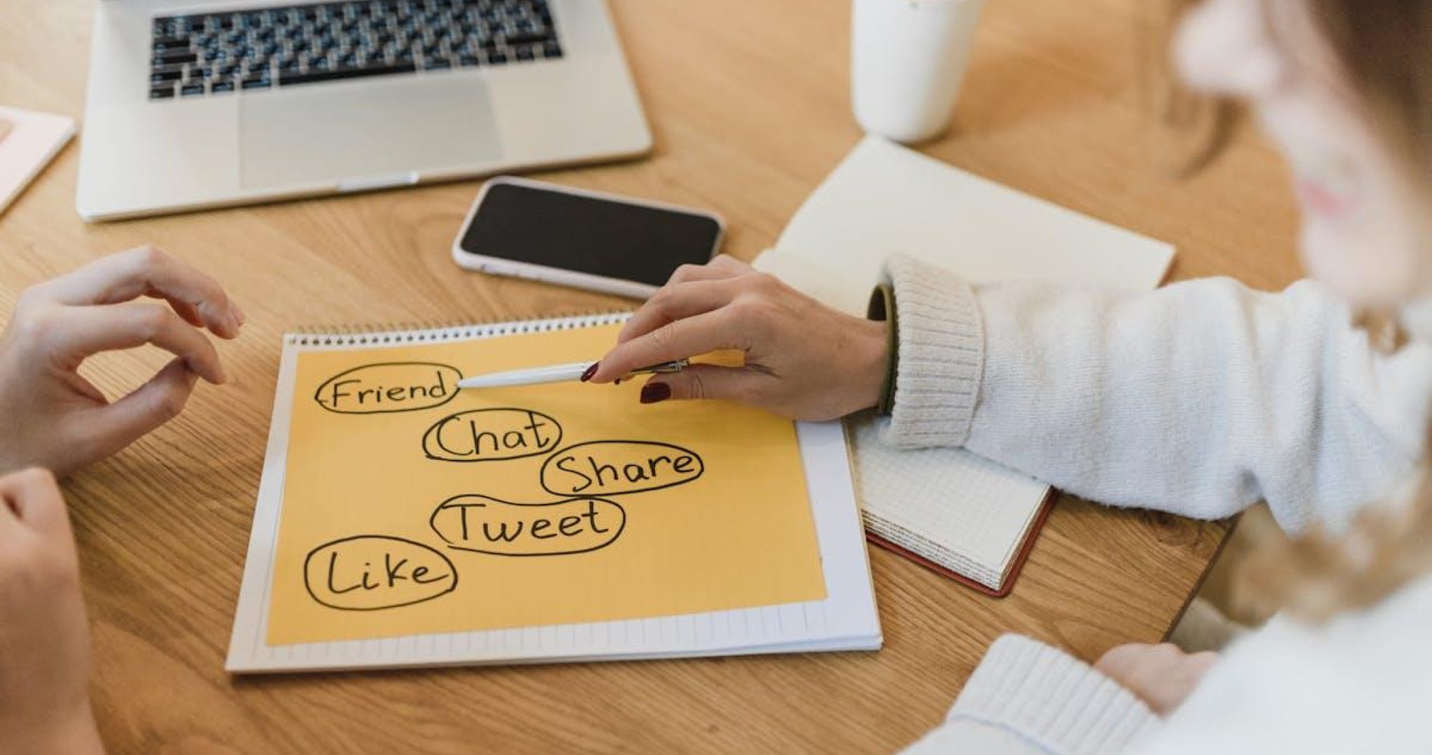 Two women planning social media marketing strategy with laptop and smartphone