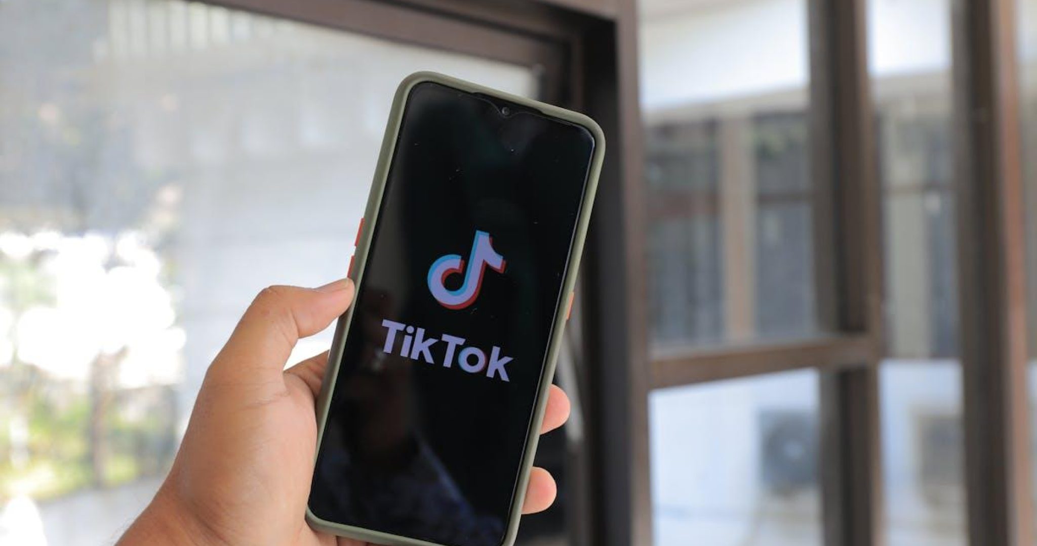 Person holding smartphone displaying TikTok app