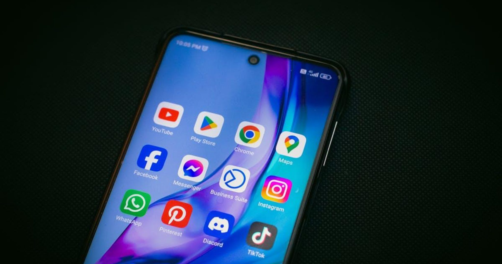 Smartphone displaying TikTok and social media app icons on dark background