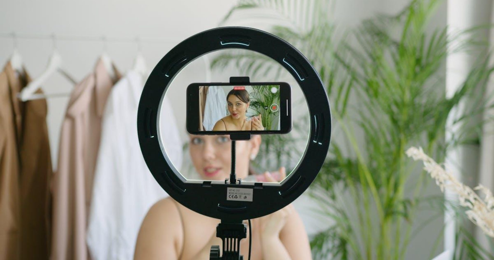 Woman recording video content with smartphone and ring light for social media UGC