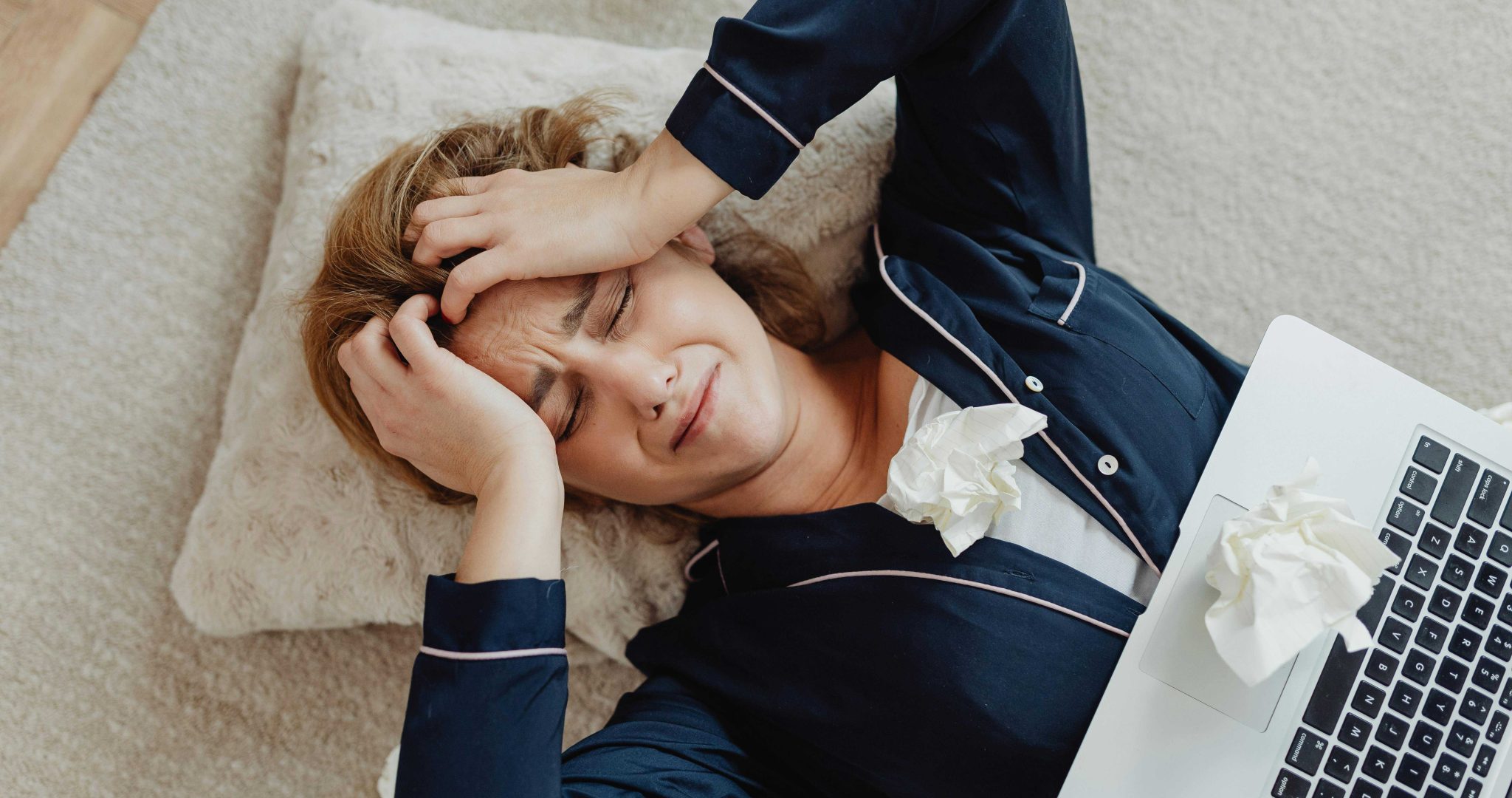 Overhead view of a frustrated woman with a laptop and crumpled papers facing remote work stress