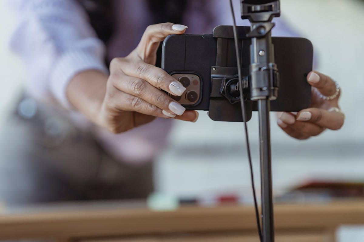 Person setting up smartphone on tripod to record video content for social media