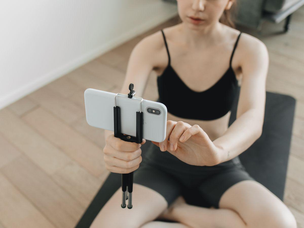 Woman filming her workout session using a smartphone on a tripod