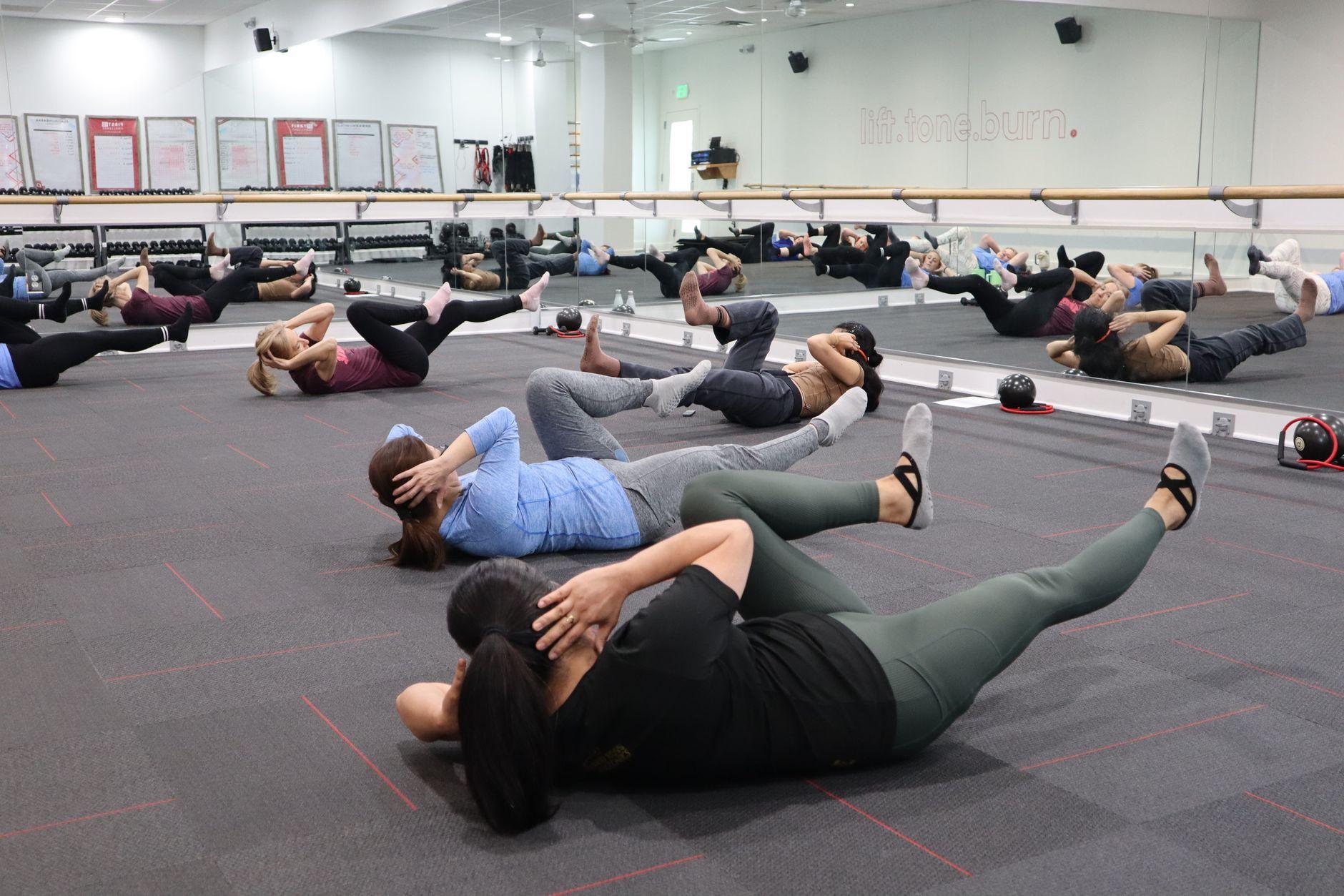 Skupina odraslih pri fitnes uri v zaprtih prostorih