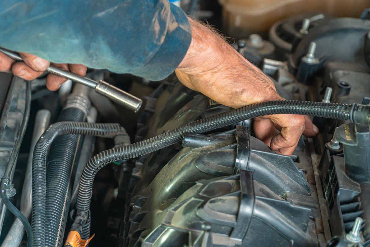 Mechanic repairing a car engine with tools
