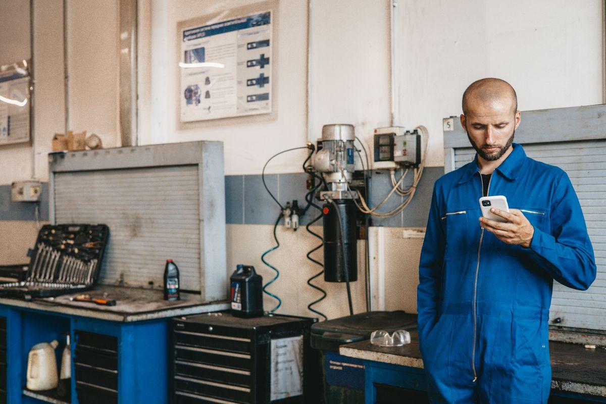 Mechanic using smartphone in auto repair workshop