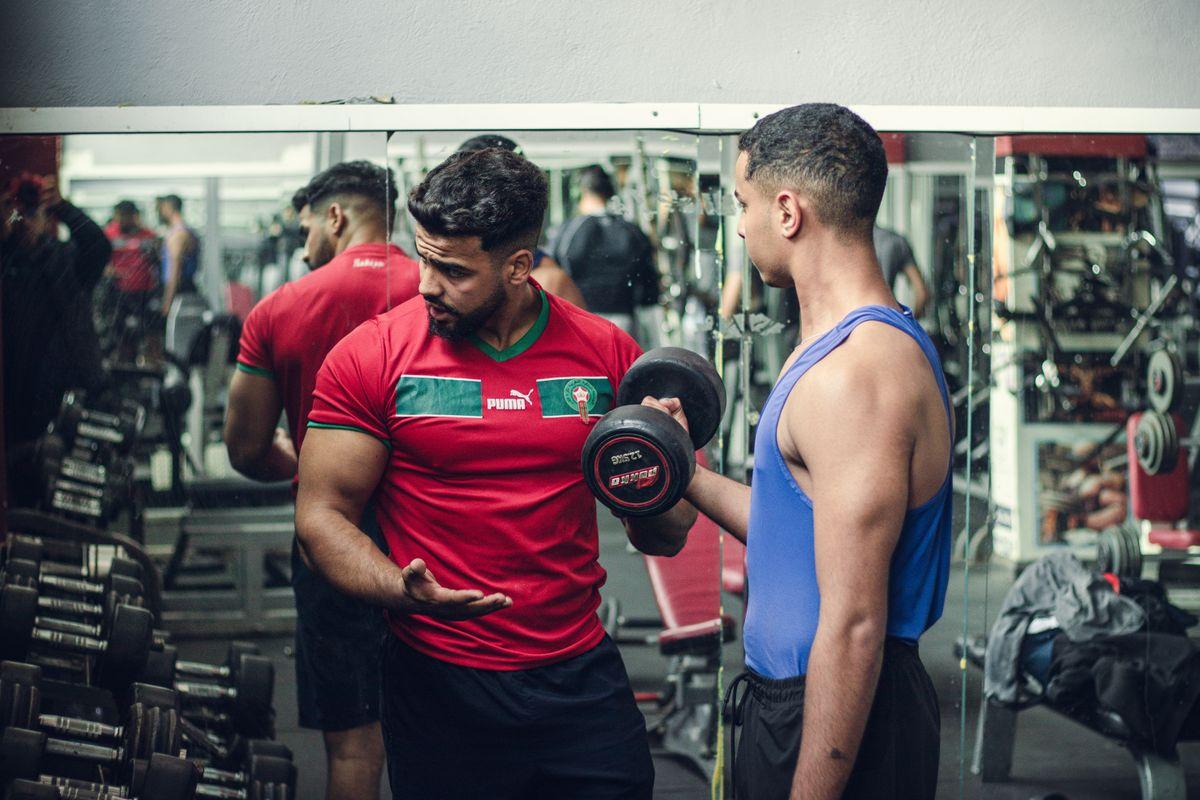 Fitness trainer guiding a client through weight training with proper technique