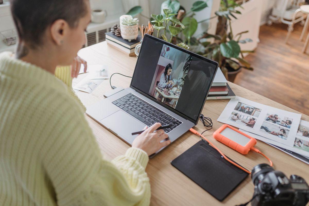 Photographer editing photos on laptop with graphics tablet