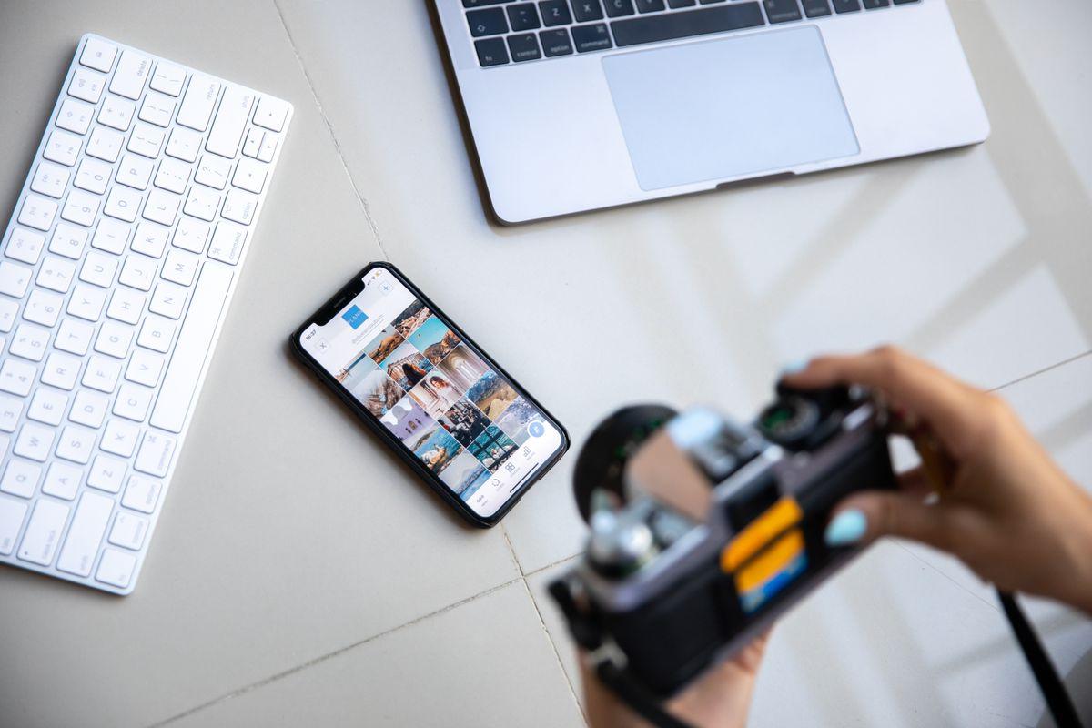 Photographer working with camera, smartphone and laptop for social media