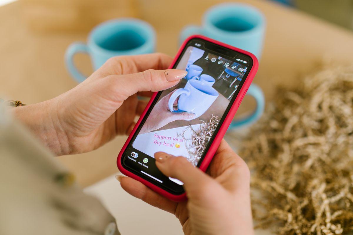 Close-up of hands using a smartphone to support local businesses online