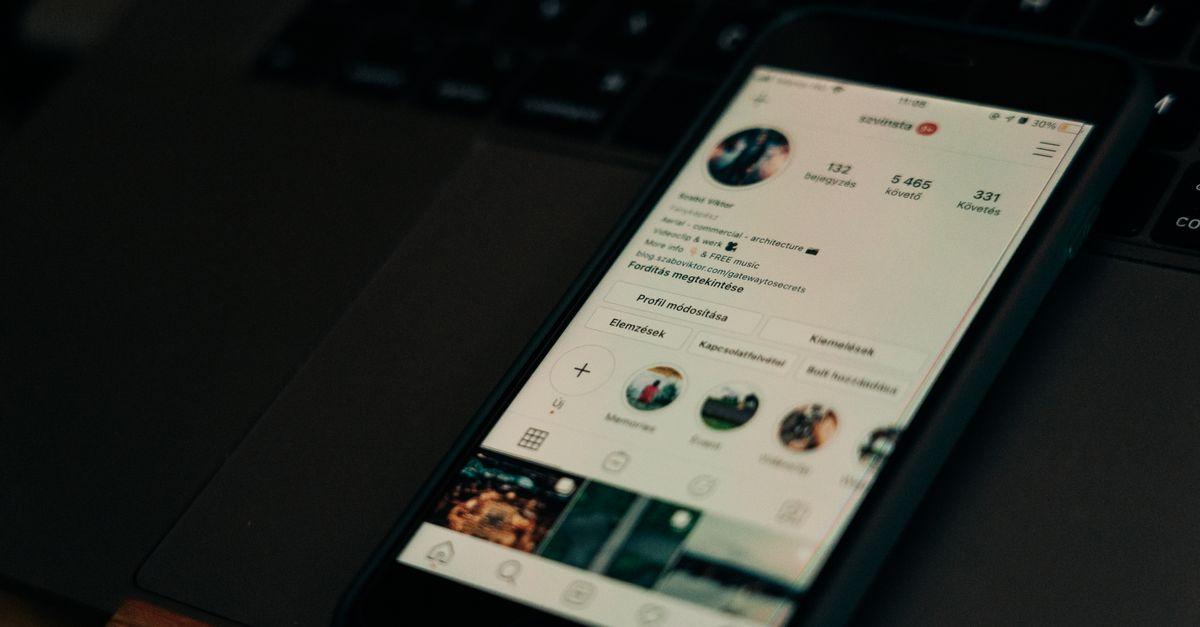 Smartphone showing social media next to a laptop