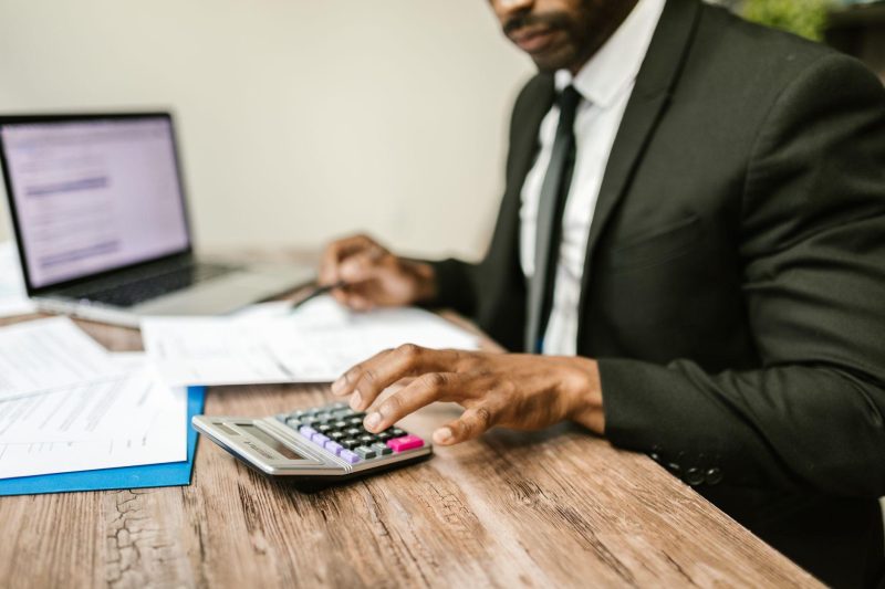 Accountant analyzing financial documents at desk with calculator and laptop