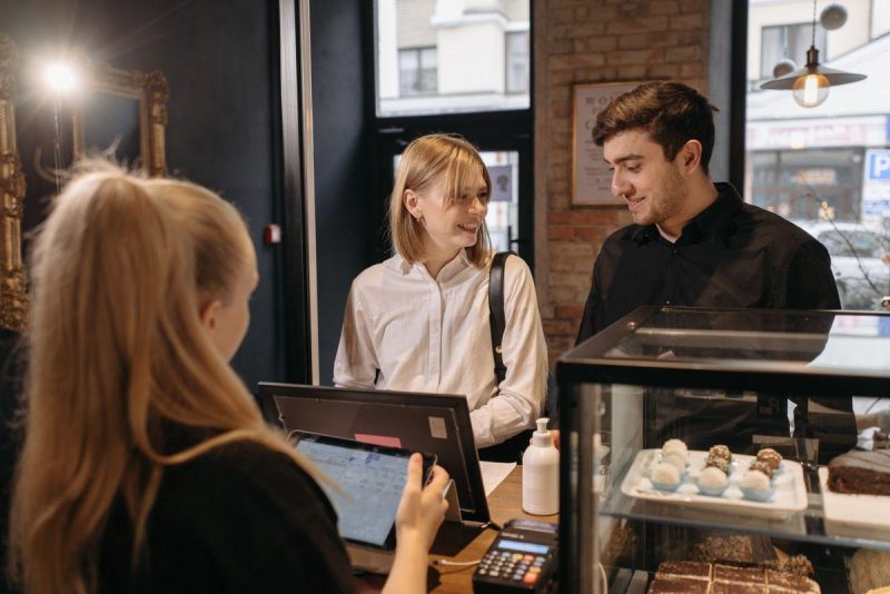 Small business barista interacting with a customer at the counter, representing social media customer service