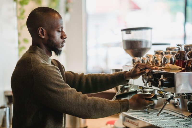 A barista expertly brews coffee on an espresso machine in a warm, inviting cafe environment