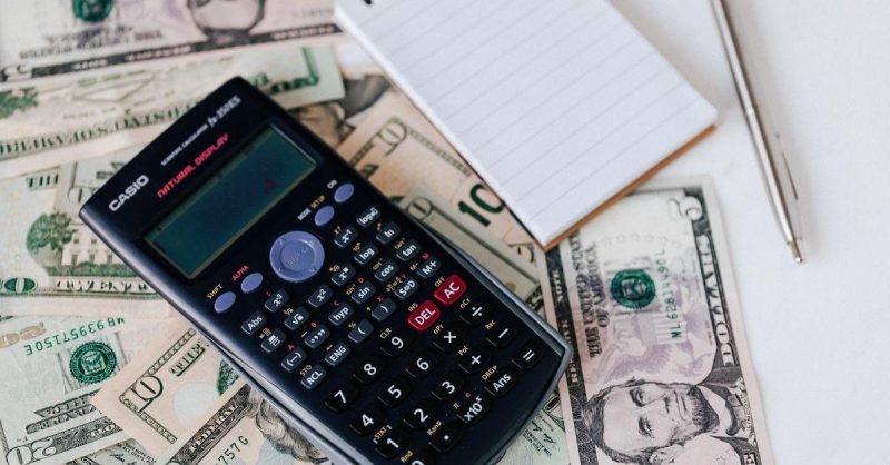 Calculator and notepad on dollar bills for business budget planning