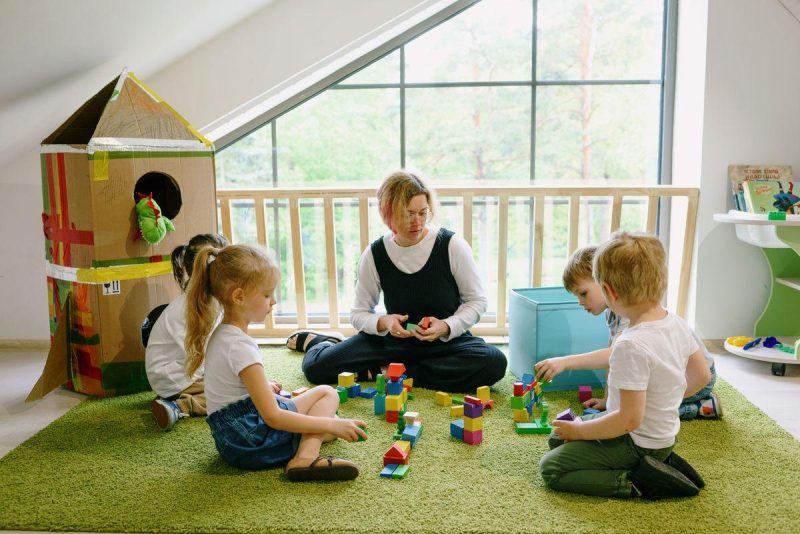 Children enjoying playtime with blocks and cardboard house in a cozy classroom