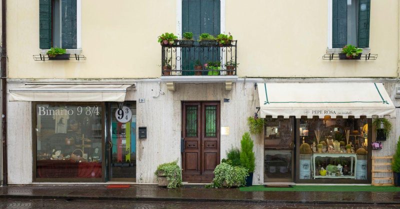 Quaint European boutique shops with elegant balconies and vibrant displays along a cobblestone street