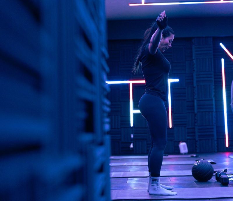 Person exercising in a modern fitness studio with neon lights