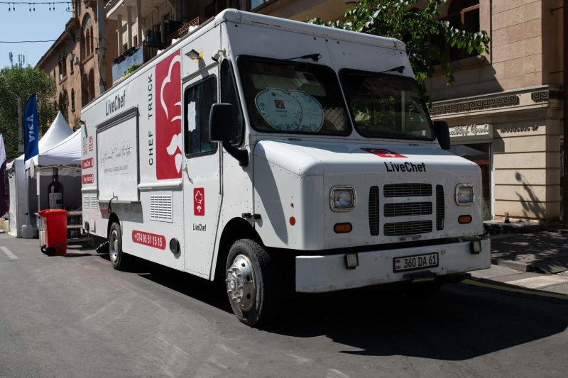 White food truck serving customers at a sunny street festival