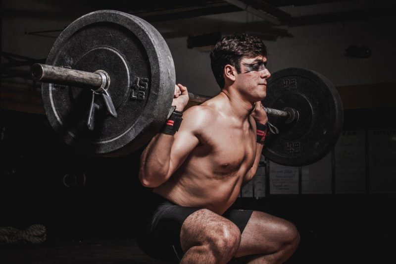 Athlete performing a barbell squat in a modern gym, showcasing strength training