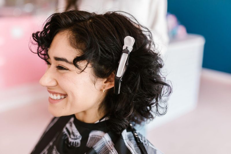 Woman with curly hair smiling in a modern hair salon