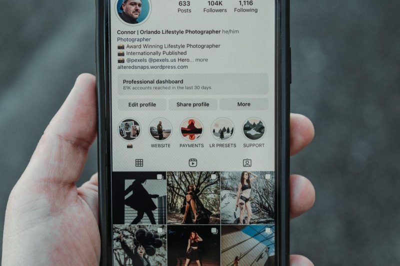 Hand holding a smartphone displaying an Instagram profile outdoors