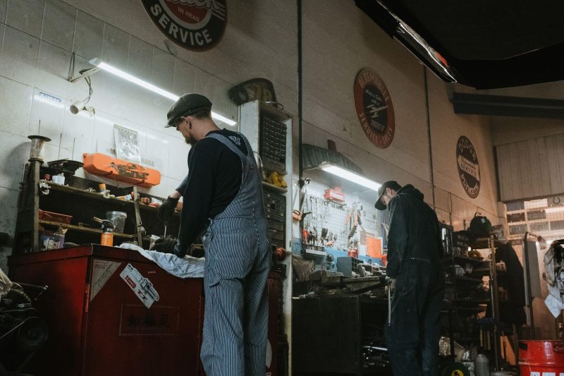 Two mechanics in a garage working on vehicle repair and maintenance