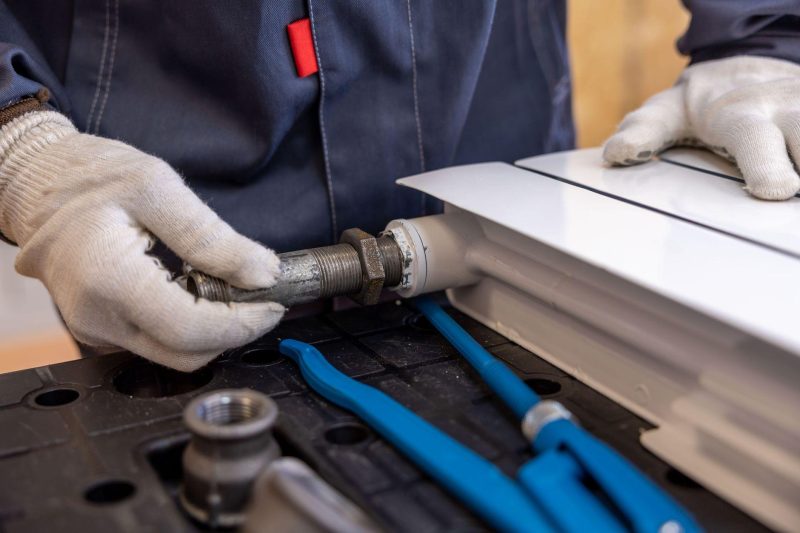 Plumber installing a radiator pipe using specialized tools
