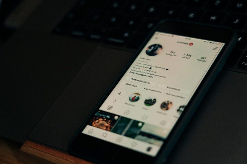 Close-up of smartphone showing social media engagement metrics next to a laptop