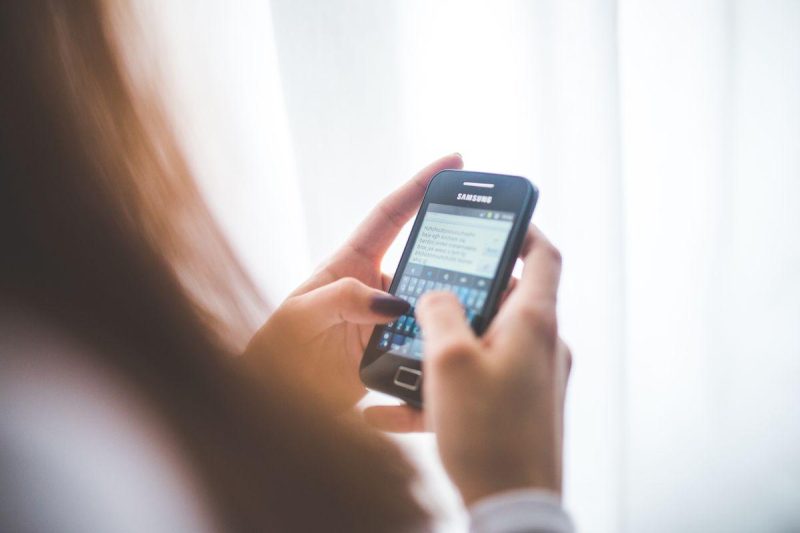A person typing a message on their smartphone, representing WhatsApp business communication
