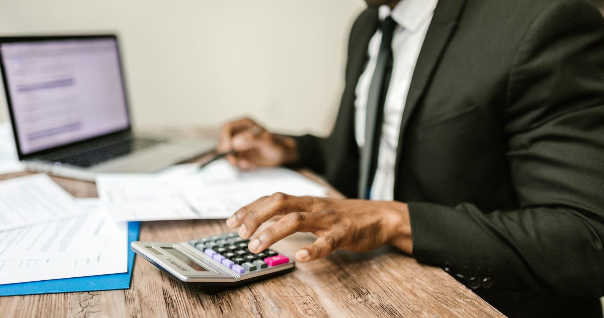 Accountant analyzing financial documents at desk with calculator and laptop