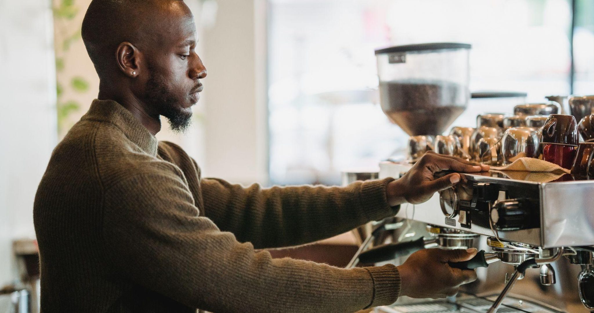 A barista expertly brews coffee on an espresso machine in a warm, inviting cafe environment