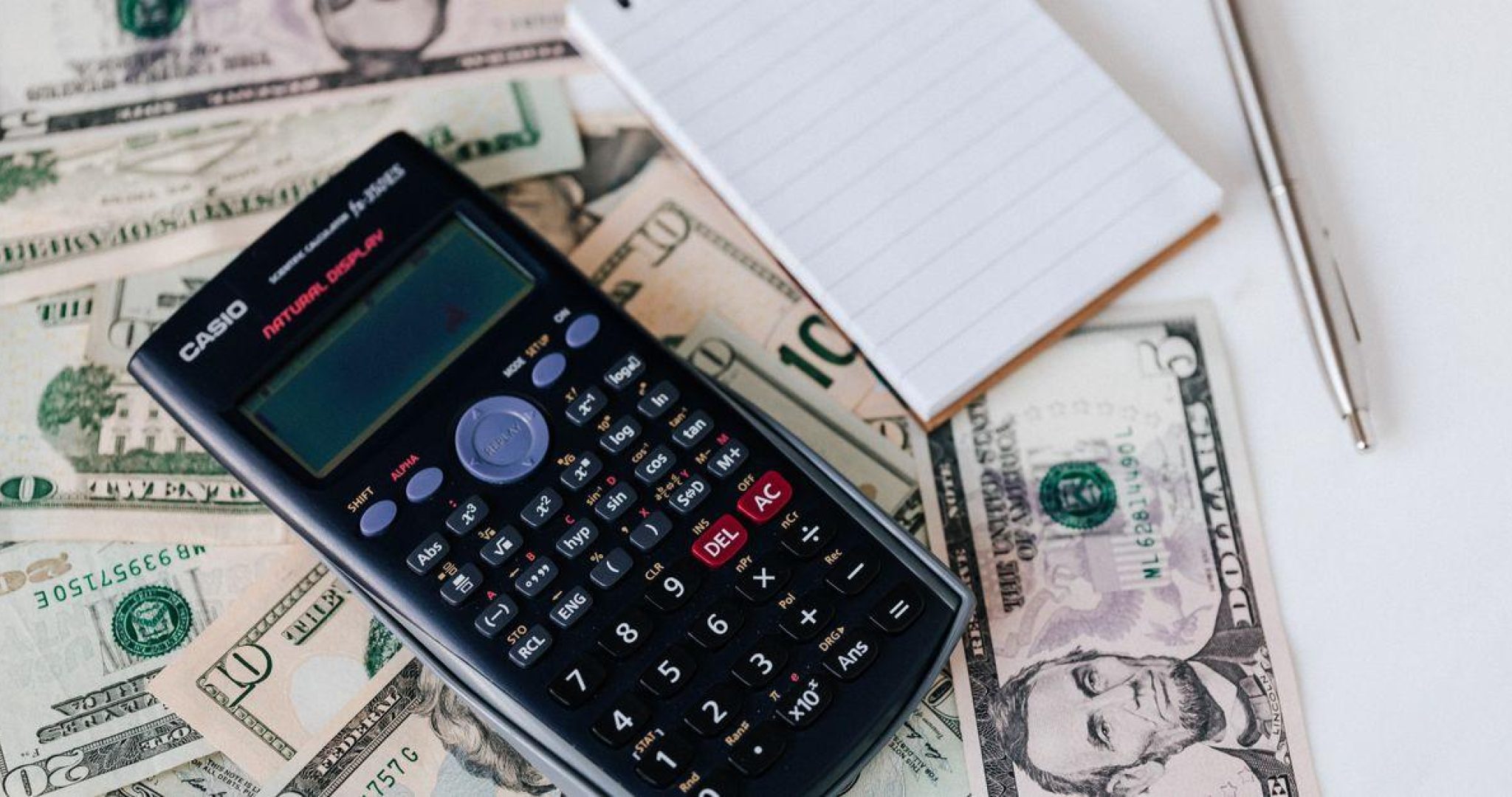 Calculator and notepad on dollar bills for business budget planning