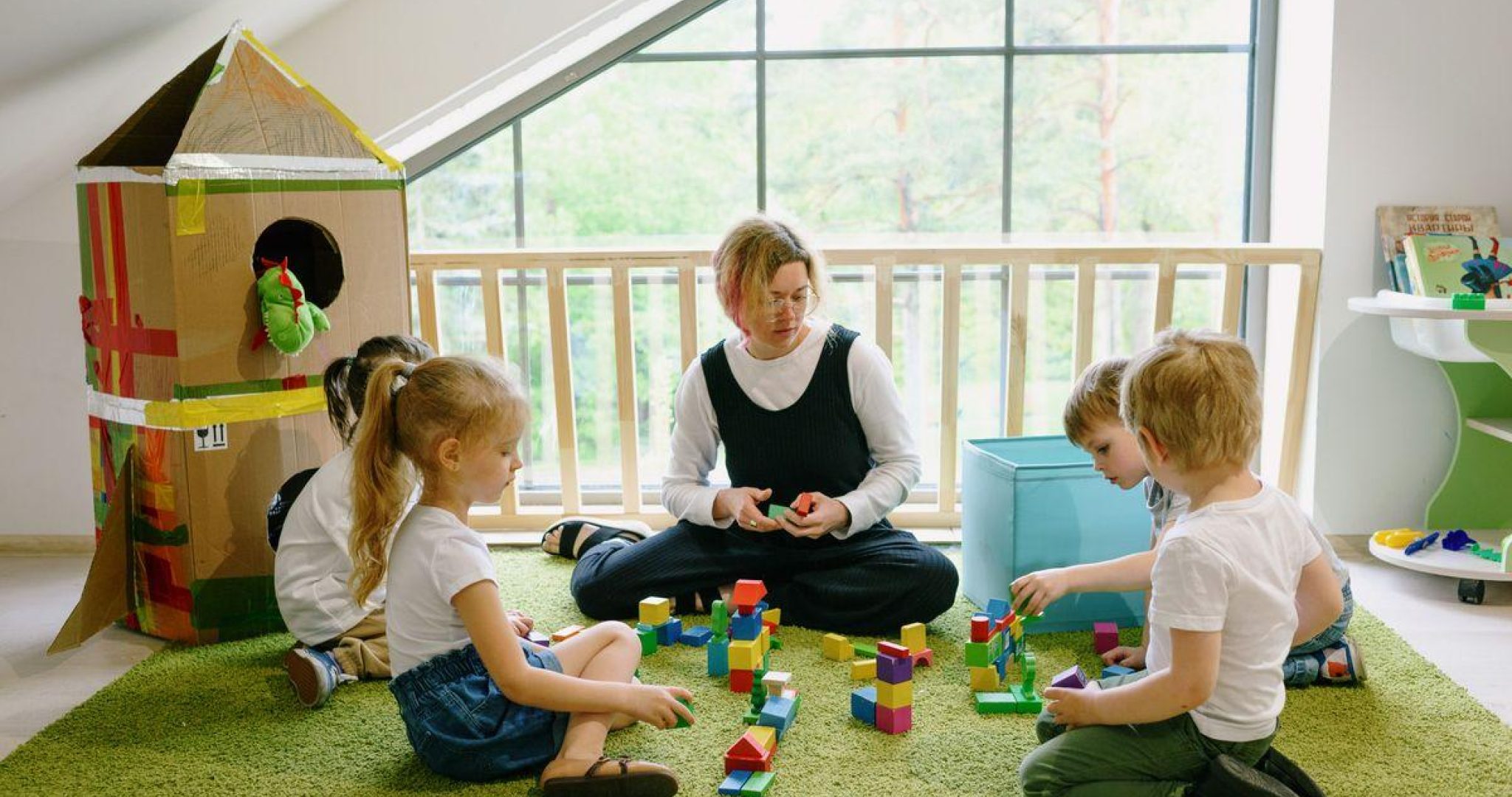 Children enjoying playtime with blocks and cardboard house in a cozy classroom